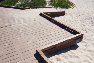 This image displays a beach access with a ramp for wheelchairs and strollers, making the beach more accessible to all individuals from the parking lot to the sand.