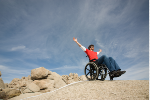 This image displays an individual in a wheelchair making it to the top of an accessible hiking trail.