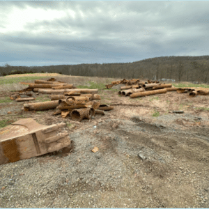 Piles of corroded and replaced sewer pipes lying in a field post-repair.